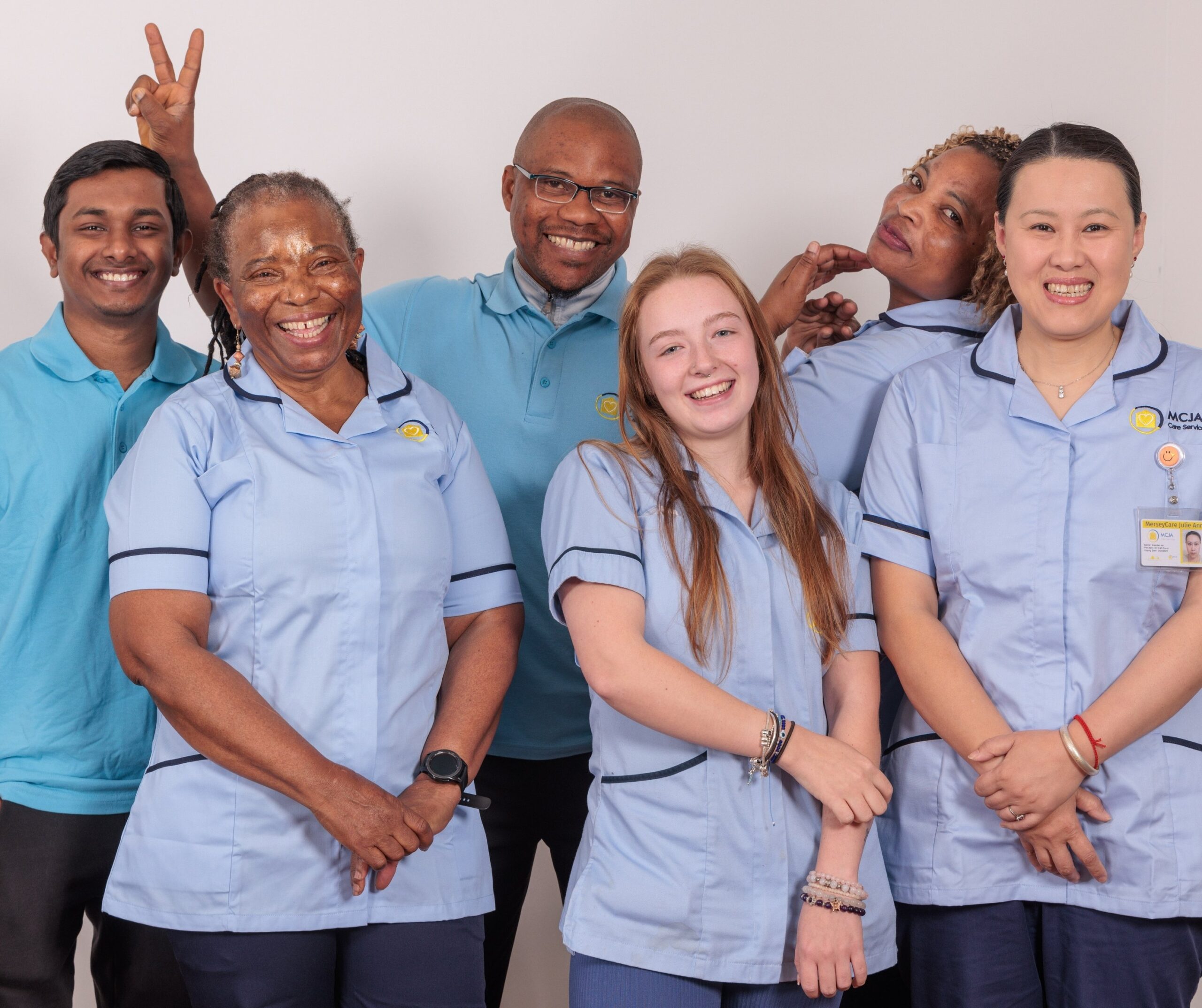 A group of 5 Care Assistants against a white wall.