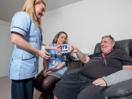 Image of 2 Care Assistants and an man in a home setting, passing over a cup of tea.