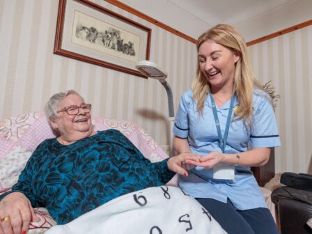 Image of a Care Assistant and an elderly lady in a home setting, holding hands.