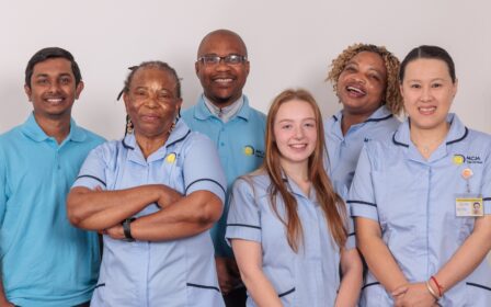 A group of 5 Care Assistants against a white wall.