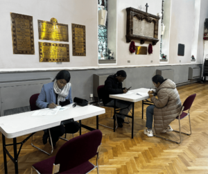 Candidates filling in application forms at a recruitment event at a local community centre.